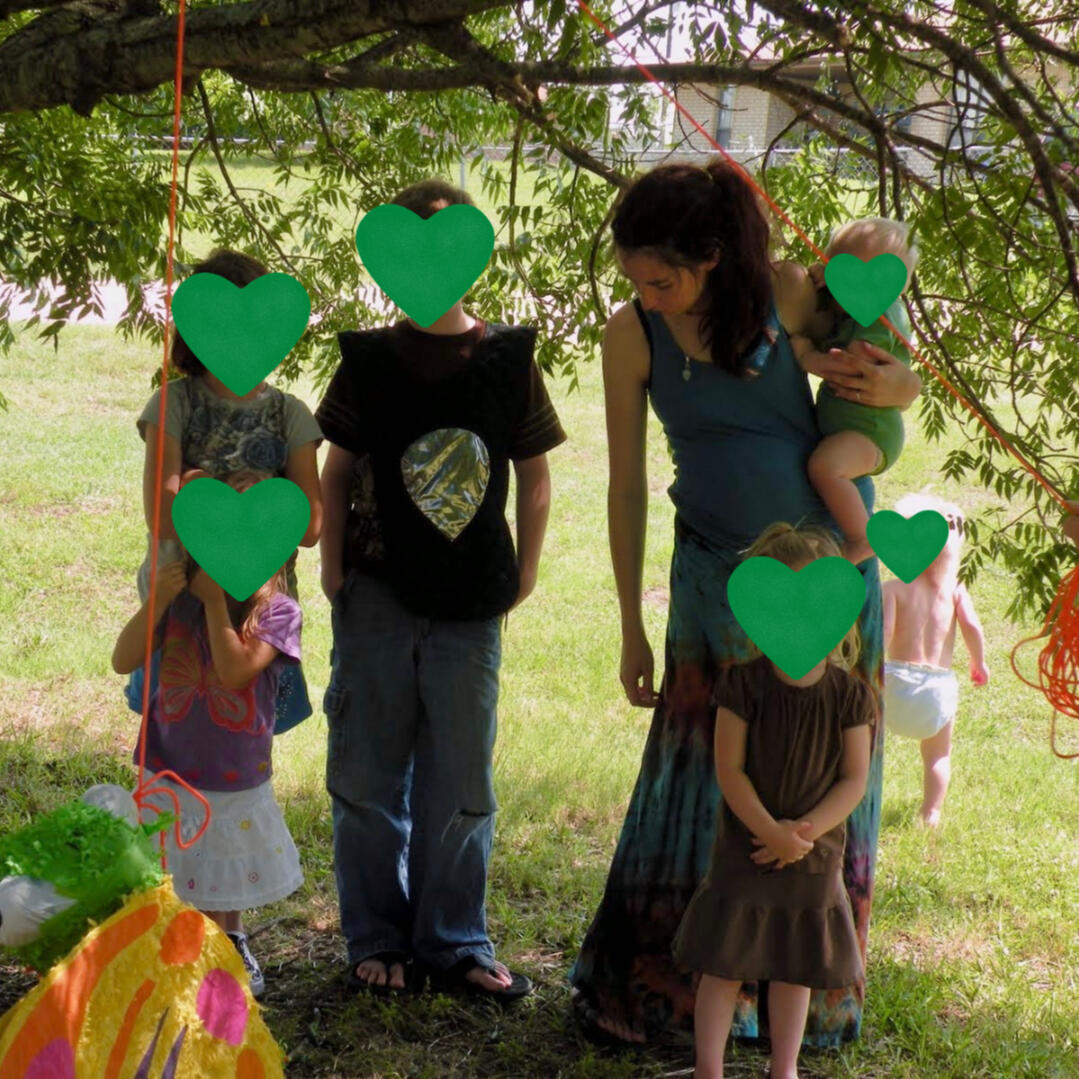 a scene of motherhood, summer 2011 Krystal Linnea, surrounded by 4 of her 5 children and 2 friends' children, putting up a piรฑata at an outdoor party.